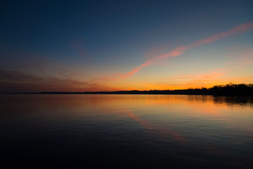 Sunset over the water with reflection off calm lake