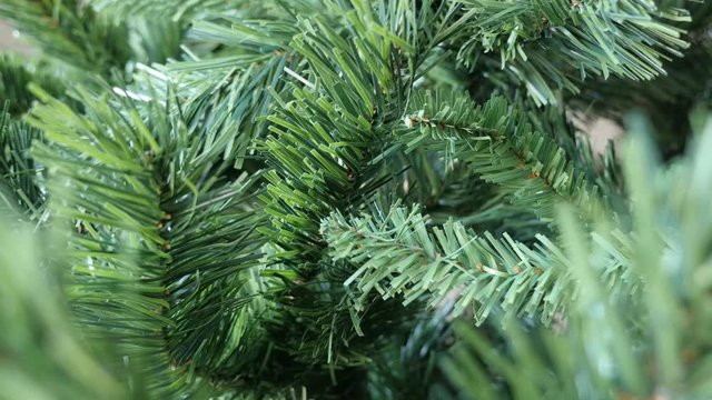 Close-up of realistic decorative spruce details slow tilt 4K 2160p 30fps UltraHD footage - Christmas tree artificial branches with green needles 3840X2160 UHD tilting video 