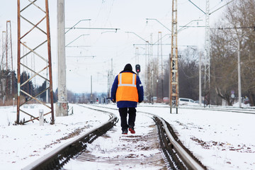 railroad worker in orange uniforms walking on the tracks.