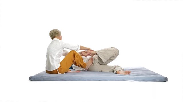 4k footage, woman stretching man leg and back with thai yoga massage isolated on white
