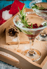Christmas refreshing alcoholic drink with cranberries and rosemary on wooden background, with gift and decorations 