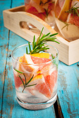Refreshing summer detox cocktail of grapefruit and rosemary, on wooden rustic table, copy space