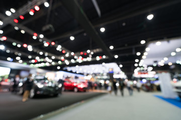 Blurred, defocused background of public event exhibition hall showing cars and automobiles,...