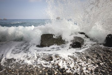 Deep blue sea waves splashing volcanic rocks, Sicily coast