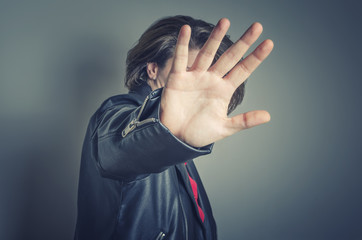 No pictures, please. Celebrity is hiding face with a hand from newspaper photographer.