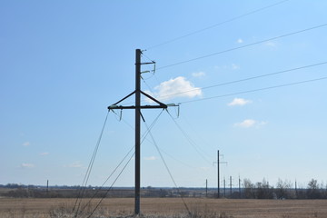 transmission line on the field with vesennney dry grass on a background of blue sky, landscape, wires, pole, power, power, electricity 