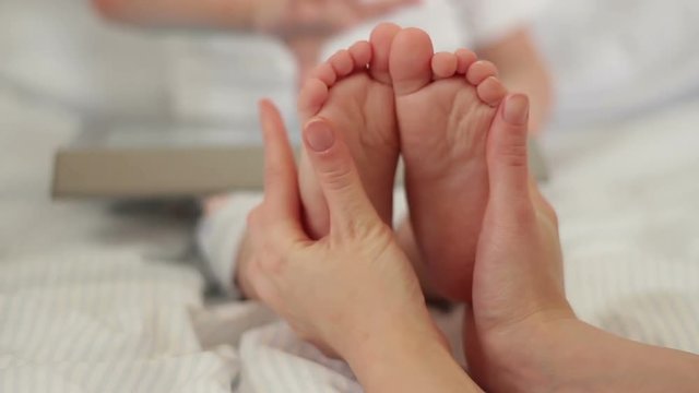 Mother holds baby feet in her hands.