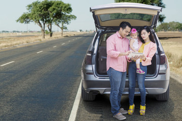 Family standing behind car with tablet