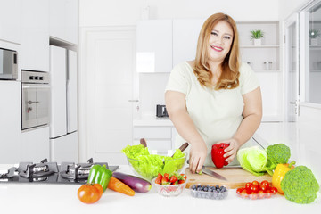 Fat woman making salad with vegetable