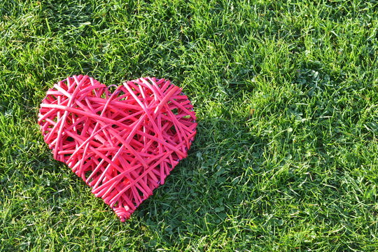 Red straw heart on the grass. Valentine's Day.