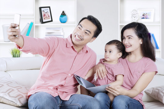 Happy family taking selfie picture on sofa