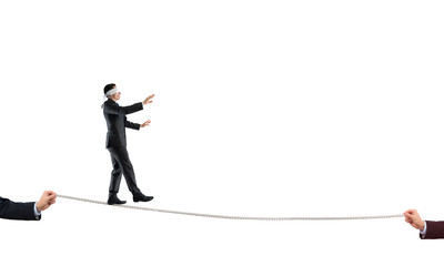 Fototapeta premium Young businessman in blindfold against white background walking on rope