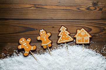 Christmas Background Theme. Ginger Men In The Snow Next To The House And Tree. Close-Up. Free Space For Text. Wooden Background. Top View.