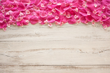 Wooden background with rose petals and hearts