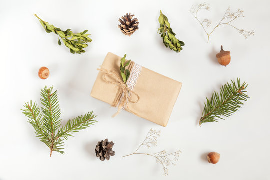 Christmas and New Year composition. Christmas gift, fir tree and buxus boxwood  branches, acorn, hazelnuts, cones and gypsophila flowers. Flat lay on white background, top view
