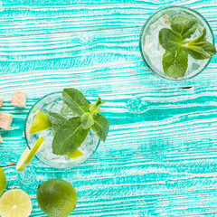 mojito in glasses with ice cubes,  decorated by mint leaf, lime fruits on turquoise colored wooden...