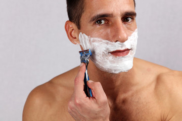 Man shaving his face with the razor blade through shave foam. Men skin care concept.