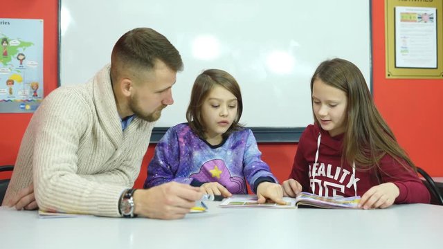 a young teacher explains teaching material two Schoolgirls