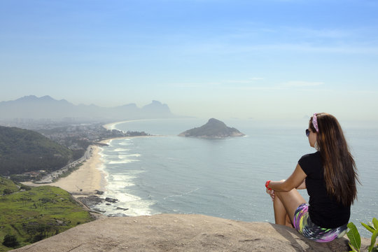 A young hiker looking out from the viewpoint over Pontal and Recreio dos Bandeirantes beaches in Barra da Tijuca, Rio de Janeiro, Brazil