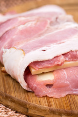 Closeup macro view stuffed meat with yellow cheese in bacon