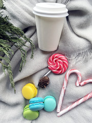 Winter coffee take away. White cooffee to go on grey blanket with macaroons. 