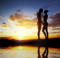 Silhouette of a loving couple over sunset background
