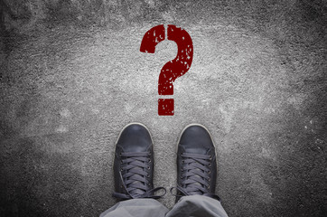 Question mark stencil print on asphalt road with sneakers