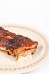 Melted yellow cheese in rolled steak with bacon