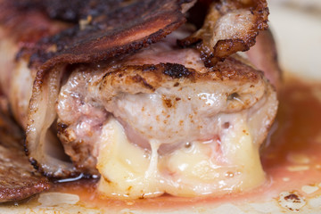 Slice of steak stuffed with yellow cheese rolled in bacon