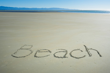 the word BEACH written on sand
