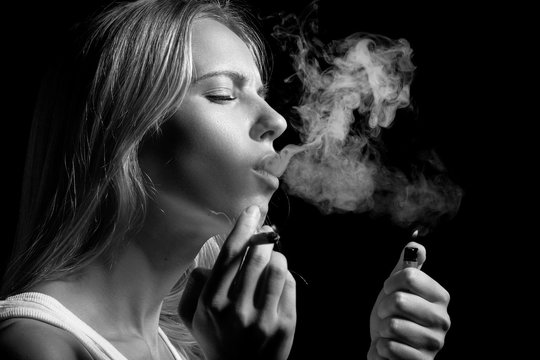 blond young woman smoking on black background, monochrome
