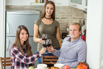 Group of young people is toasting with red wine at holiday dinner party at home.