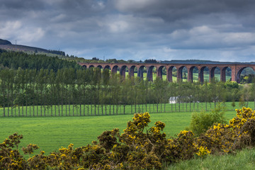 Inverness, Scotland - June 2, 2012: The long Culloden train viaduct is collection of red-stone bows...