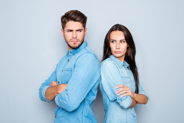 Serious man and woman with crossed hands standing back to back a