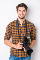 Portrait of young handsome cheerful photographer holding camera - obrazy, fototapety, plakaty