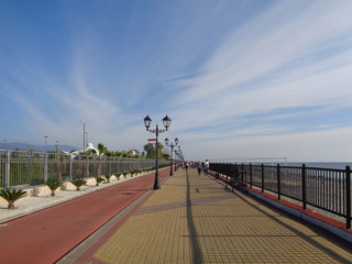 Sunny seaside promenade, blue sky with white clouds