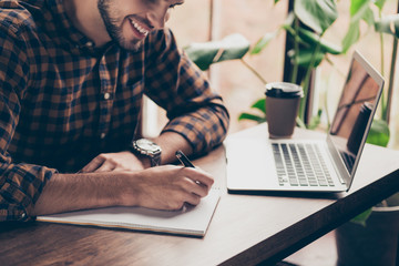 Close up of young happy man writing in his notebook