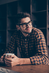 Portrait of happy minded man in glasses dreaming with cup of tea