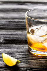 rum with ice in glass on dark background and lime