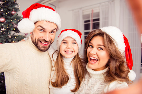 Happy smiling family wearing santa hats and making selfie