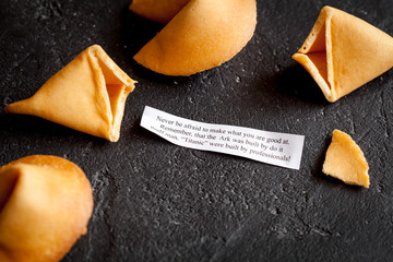 Chinese fortune cookie with prediction on dark background top view