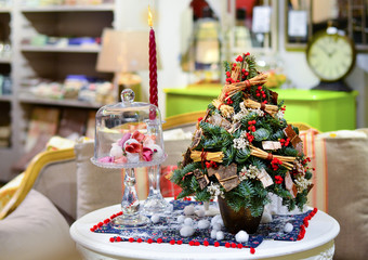 Little Christmas trees is on the table next to a candle