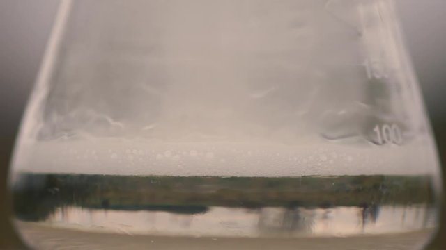 Reaction between chlorine bleach and sulphuric acid. Chemical demonstration of dangers of mixing acid and bleach cleaning products, with release of chlorine gas and sodium sulphate