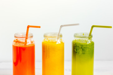 Fresh detox juices glass in row bottles on white background