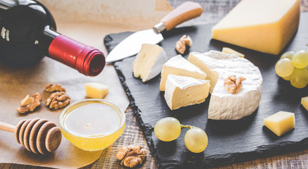bottle of red wine, appetizers and corkscrew on wooden background