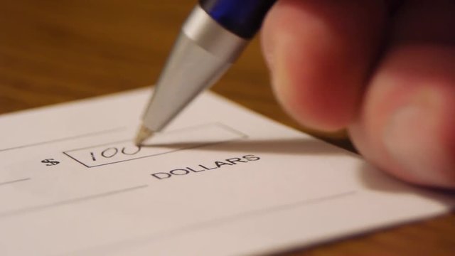 Close up check being written for one thousand dollars on table