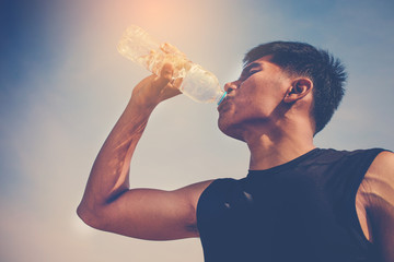 close up of a man drinking water from a bottle outside