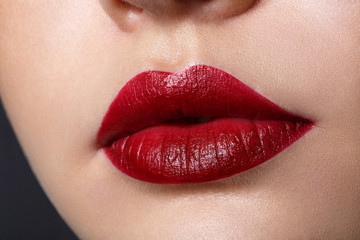 Close up view of beautiful woman lips with red matt lipstick. Cosmetology, drugstore or fashion makeup concept. Beauty studio shot.