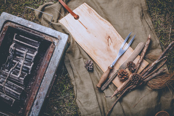 A prepared stove with charcoal inside for grilling and kitchen equipment put aside with wood block.