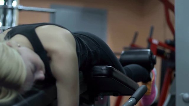 Blonde girl training at the gym. Woman engaged in fitness